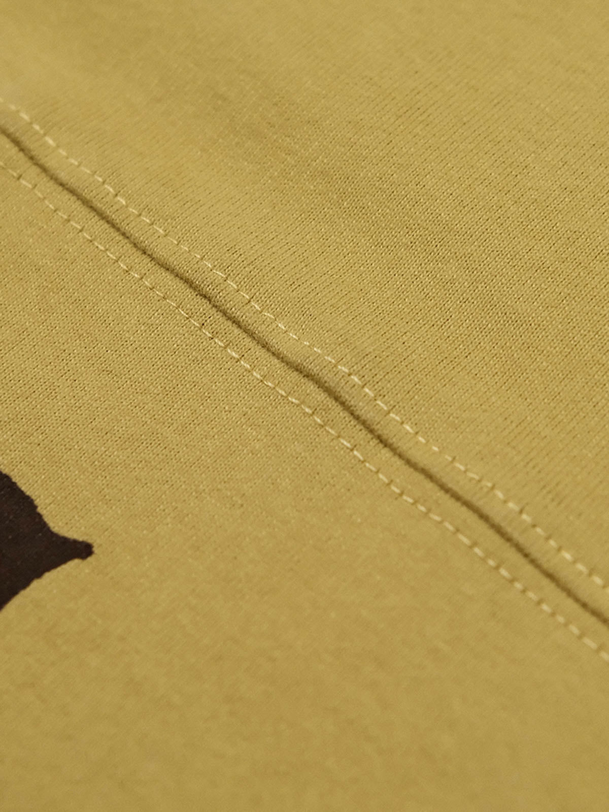 フットボールカルチャープリントTシャツの首元の小さなカラーデザインとダブルニードルショルダーラインのクローズアップ。耐久性と形状の持続性に優れたディテールが見える。