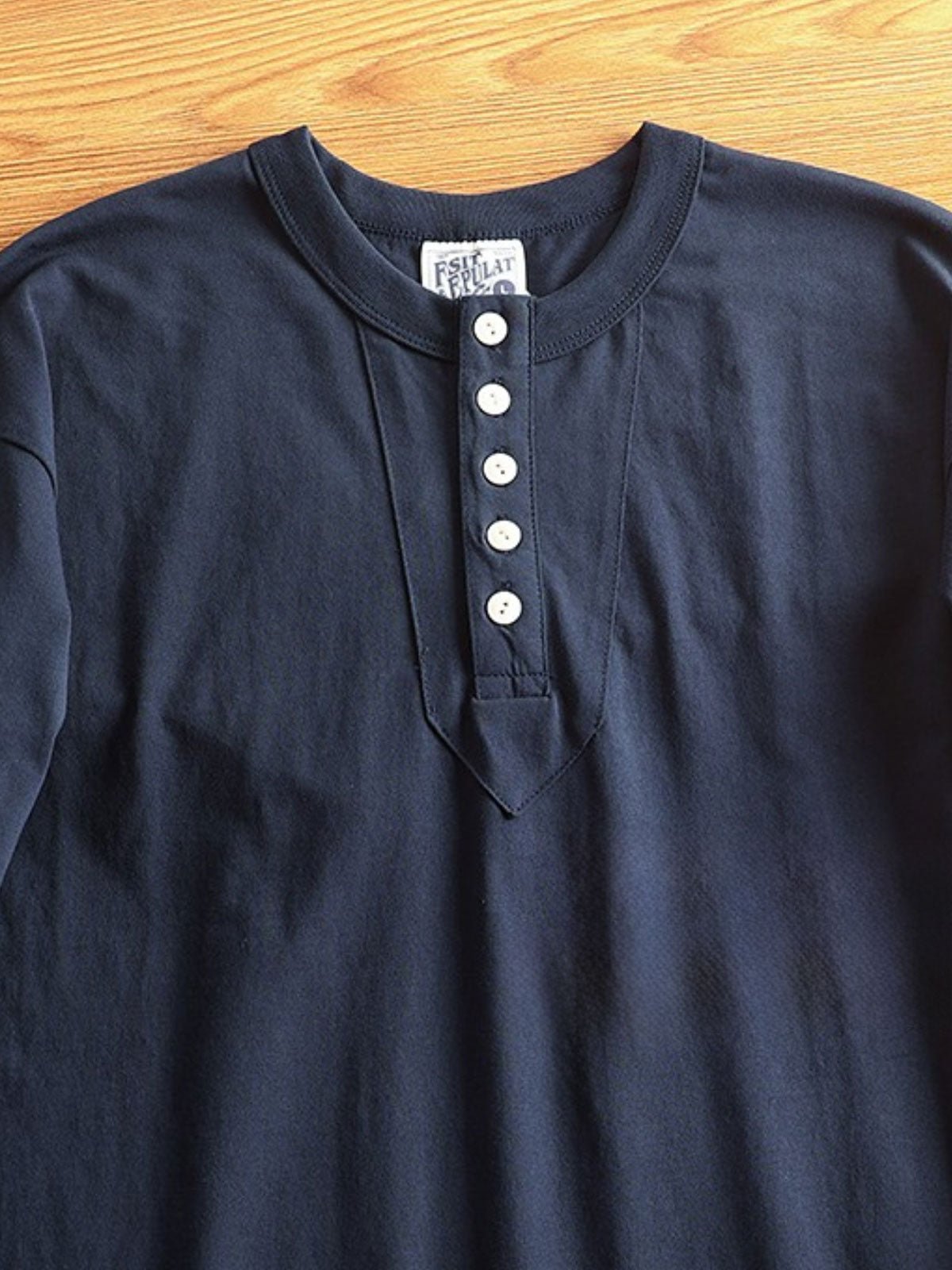 产品画像
アメカジ ヘンリーネックTシャツの全体画像。ヴィンテージ感のあるデザインとアメリカンピマコットンの質感が強調されています。
詳細画像
ヘンリーネックTシャツのディテール画像。三本針リブの襟元や、成衣洗い加工された生地の質感をクローズアップで紹介。