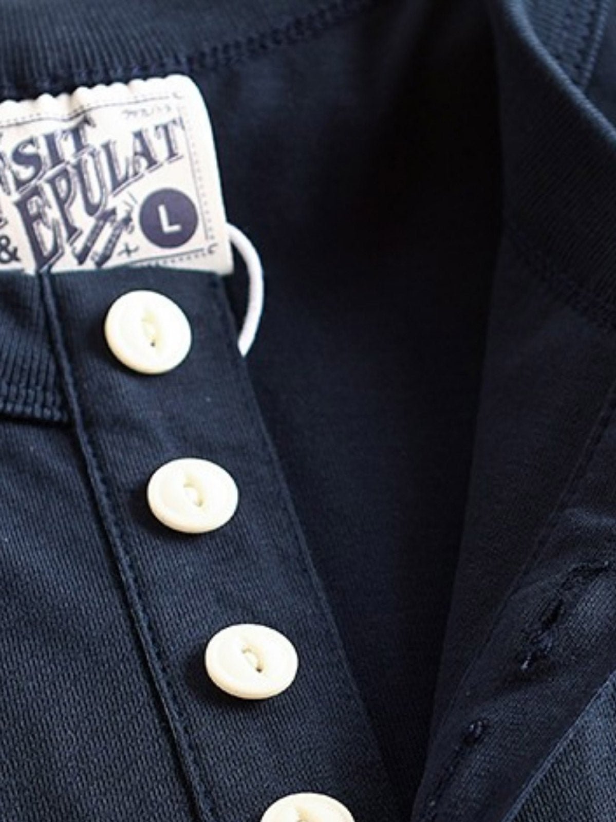 产品画像
アメカジ ヘンリーネックTシャツの全体画像。ヴィンテージ感のあるデザインとアメリカンピマコットンの質感が強調されています。
詳細画像
ヘンリーネックTシャツのディテール画像。三本針リブの襟元や、成衣洗い加工された生地の質感をクローズアップで紹介。