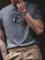 モデルがクラシックなヘンリーネック コットンTシャツを着用し、カジュアルなスタイルを披露。