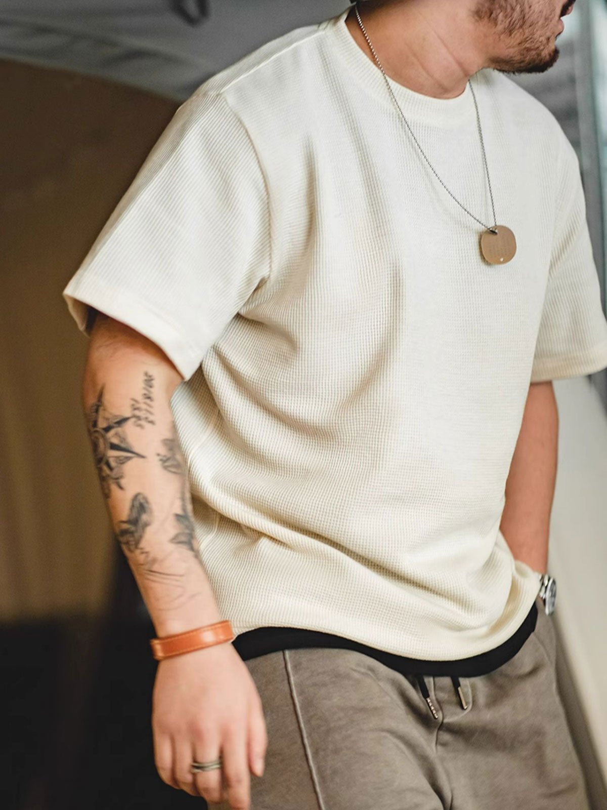 モデルがベージュのワッフル織りニットTシャツを着用。デニムパンツと合わせたカジュアルなスタイリング。