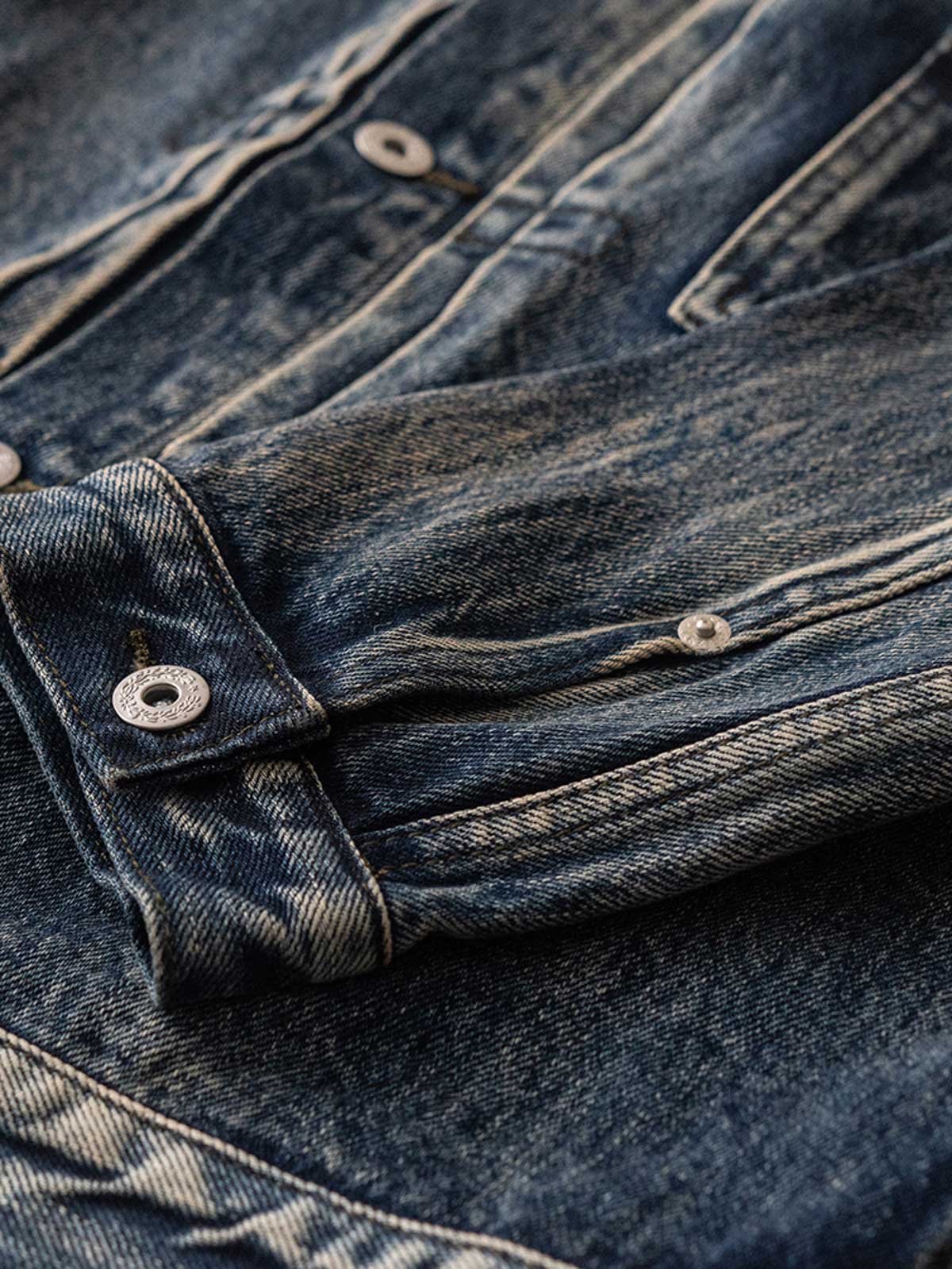 ジャケットのディテールショット、真鍮の未加工の錫メッキパリボタンとスラブデニムの質感を展示