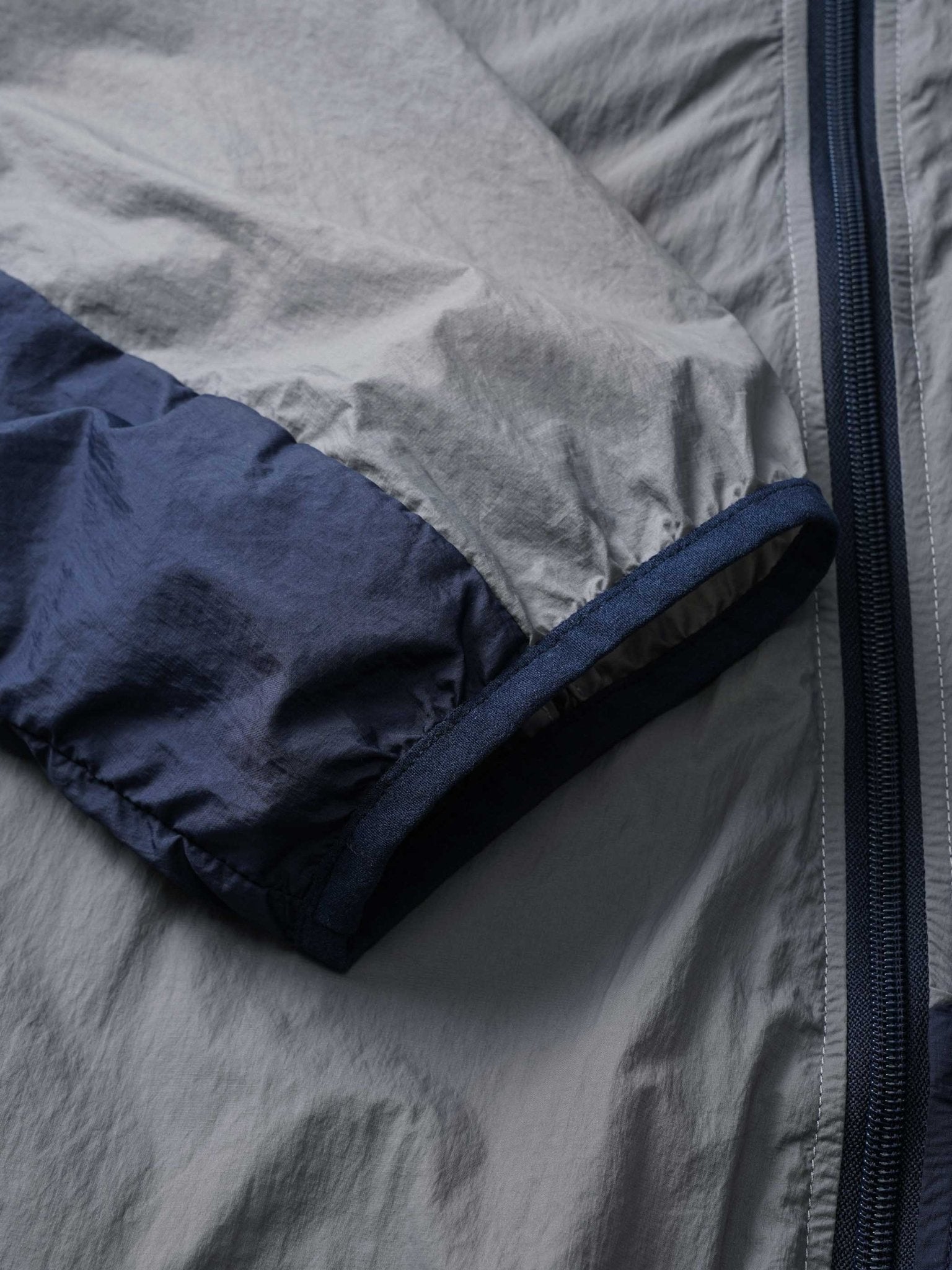 カーブ状のジッパーとサイドポケットのクローズアップ、UPF40+の紫外線対策機能を強調。