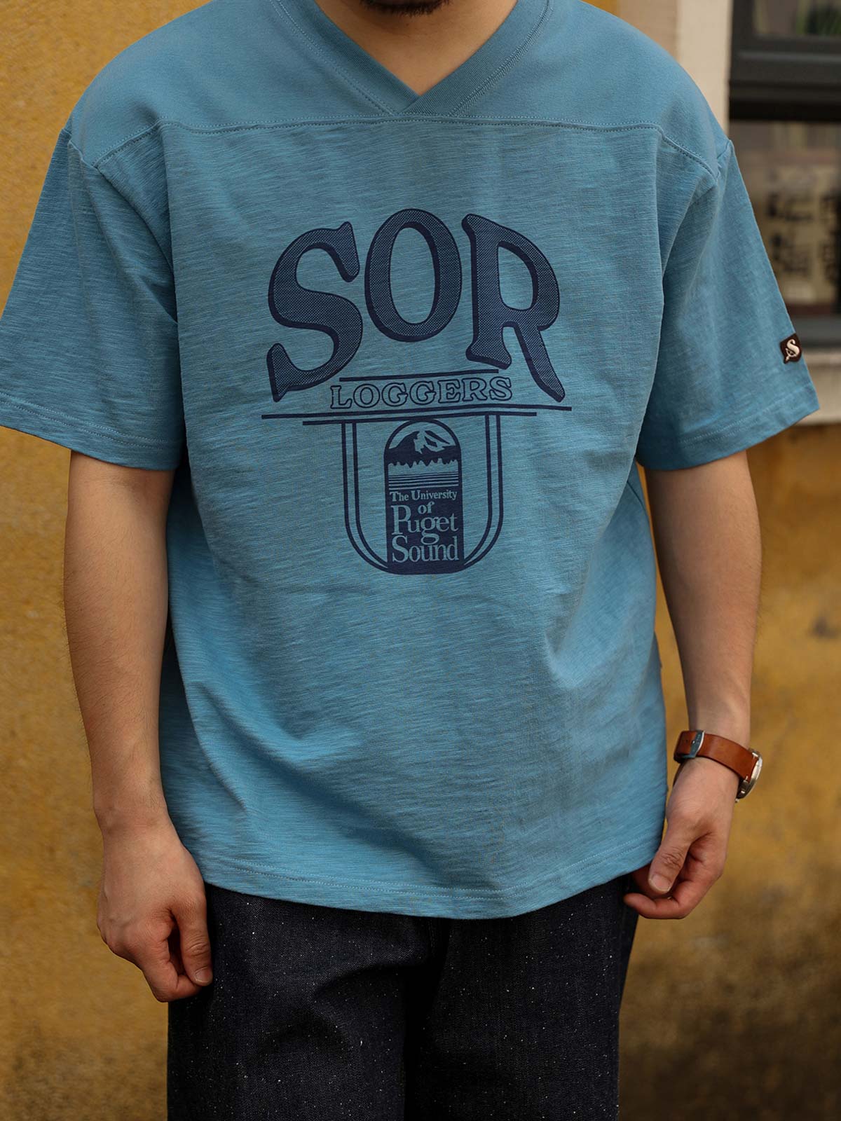 詳細画像: Tシャツの胸のプリントと肩のパネルデザインのディテール