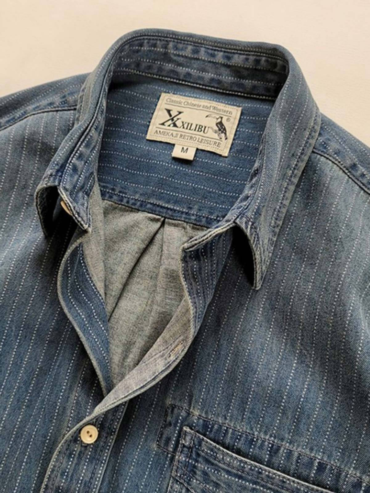 ウォッシュ加工を施したクラシックなデニム生地と緻密なストライプデザインのディテール。耐久性と洗練された印象を提供。