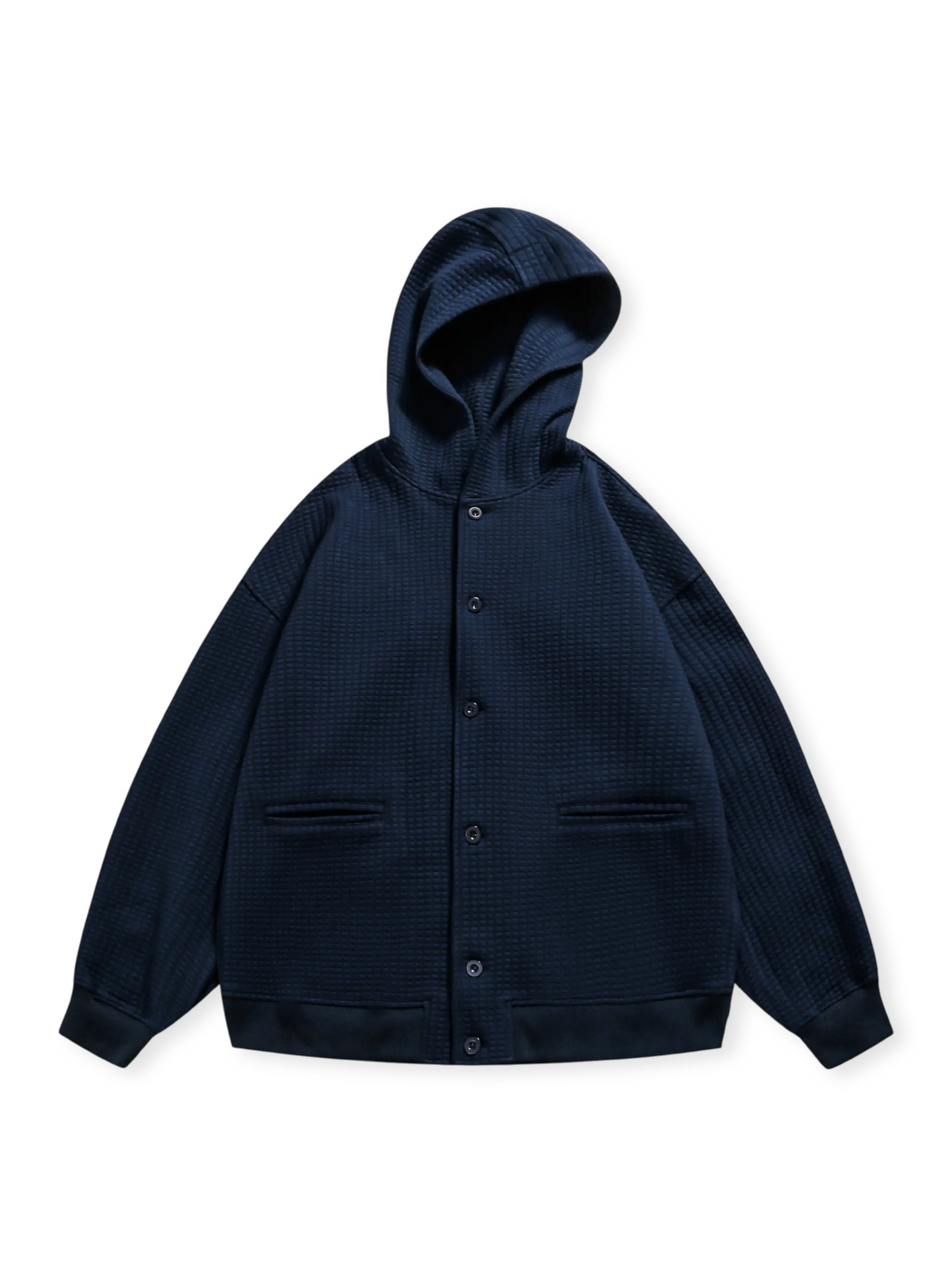 ワッフルチェックの立体織り加工を施したフーデッドジャケット。スナップボタンと収納ポケットが特徴。