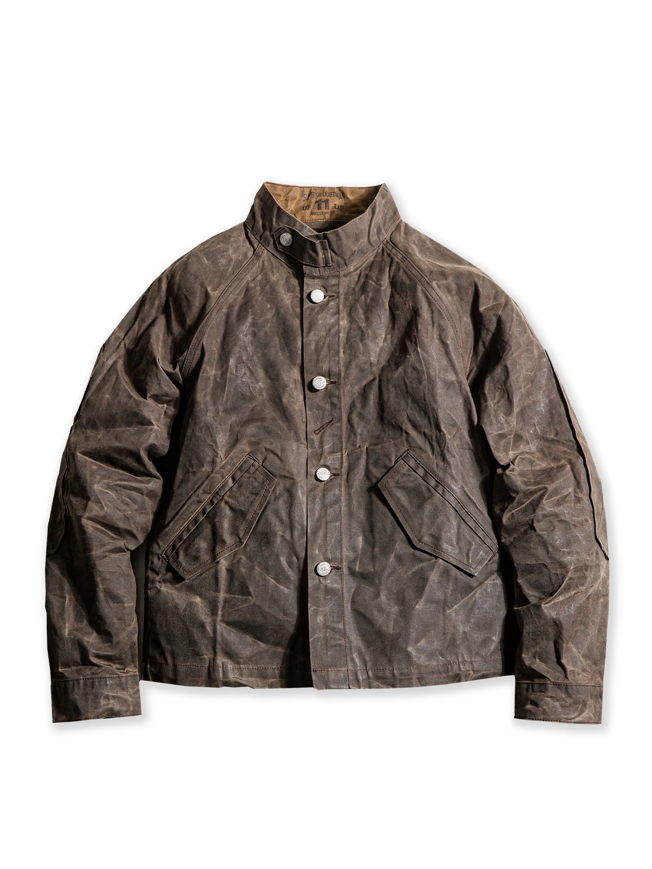 スタンドカラーとワックスドキャンバス素材を特徴とするヴィンテージミリタリースタイルのジャケット。肘の補強ステッチと実用的なスラントポケットを備え、防風・防水性に優れたデザイン。