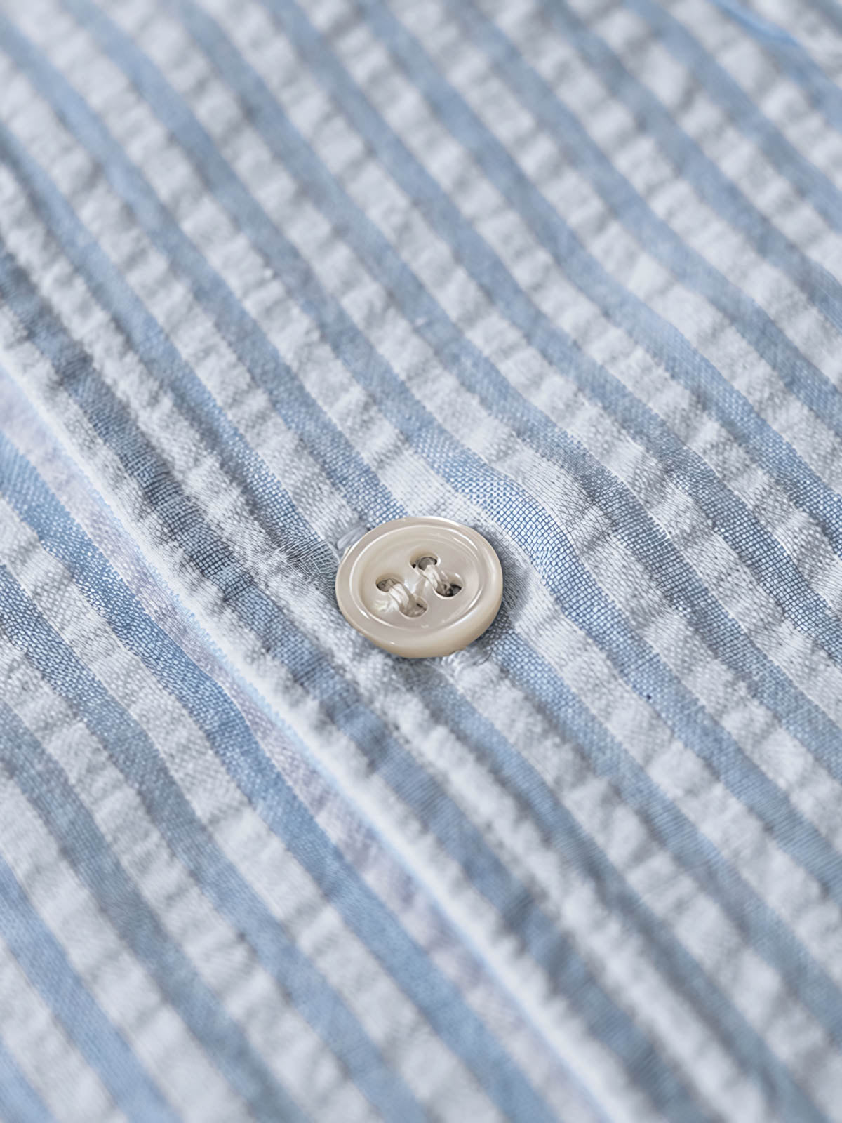 シャツのシアサッカー生地と天然シェルボタンのディテールを特集。