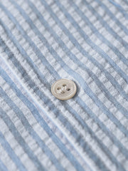 シャツのシアサッカー生地と天然シェルボタンのディテールを特集。