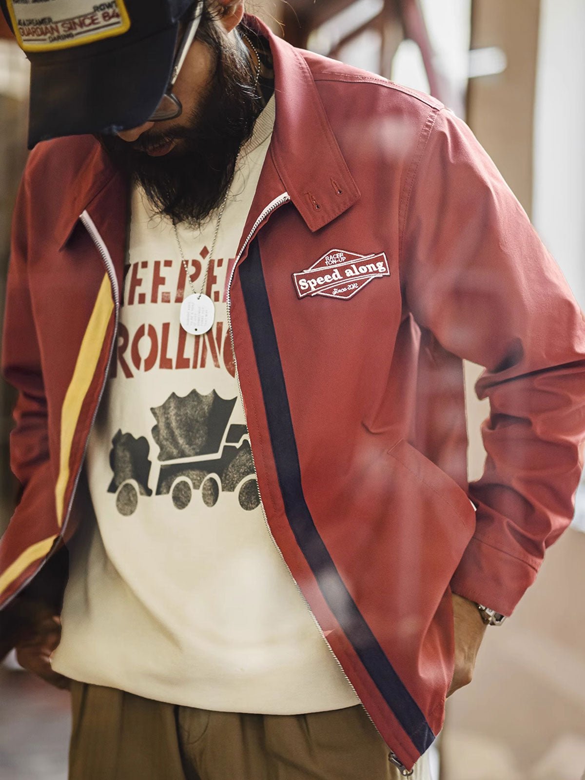 詳細画像: バイカラーのジッパーディテール、ツイル素材の高い耐摩耗性とレトロな赤色の特徴が分かる部分アップ。
モデル画像: レトロなレーシングジャケットを着用したモデル、ストリートファッションとヴィンテージスタイルを演出。
