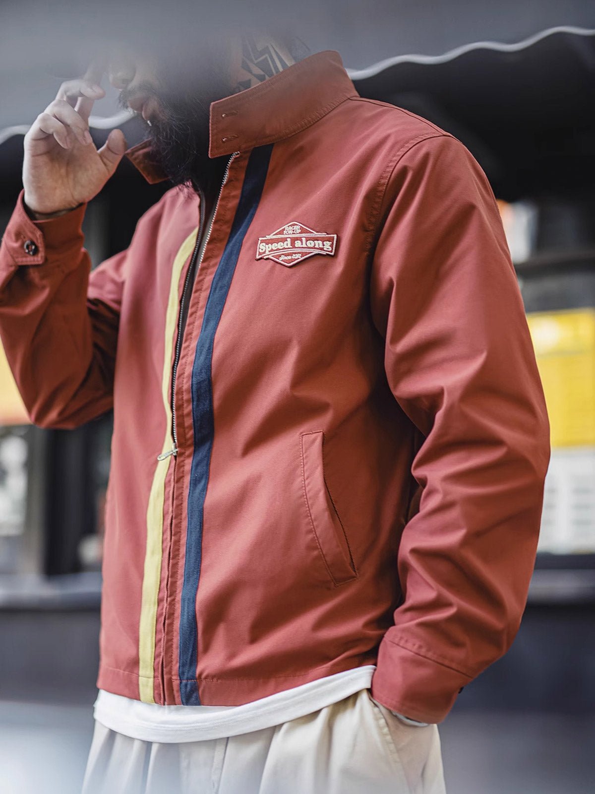 詳細画像: バイカラーのジッパーディテール、ツイル素材の高い耐摩耗性とレトロな赤色の特徴が分かる部分アップ。
モデル画像: レトロなレーシングジャケットを着用したモデル、ストリートファッションとヴィンテージスタイルを演出。