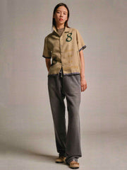 製品画像: 8周年記念プリントラフィアシャツの正面図、独特なプリントデザインとベルベットトリミングを展示