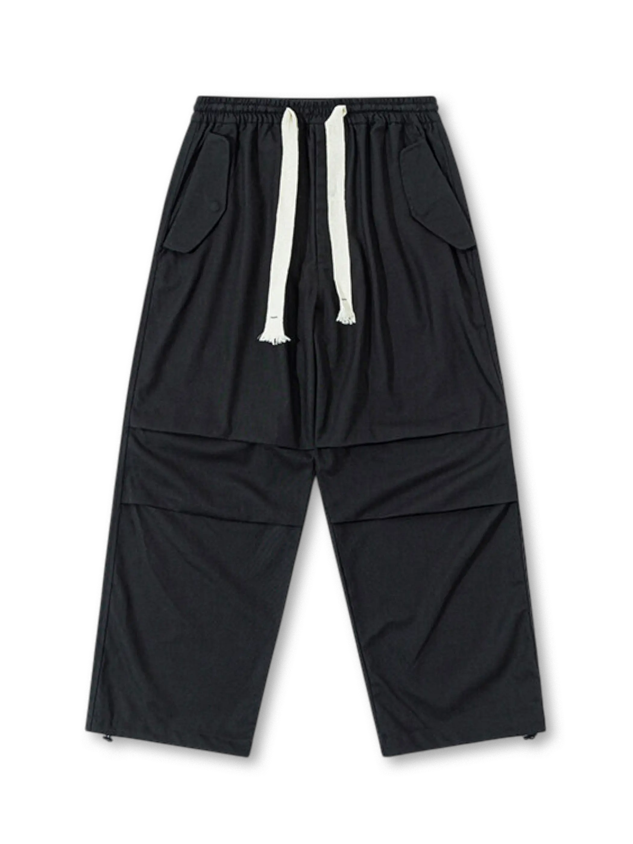  ブラックのパラシュートパンツ、両サイドに大きなフラップポケットを配したデザイン