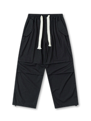 ブラックのパラシュートパンツ、両サイドに大きなフラップポケットを配したデザイン