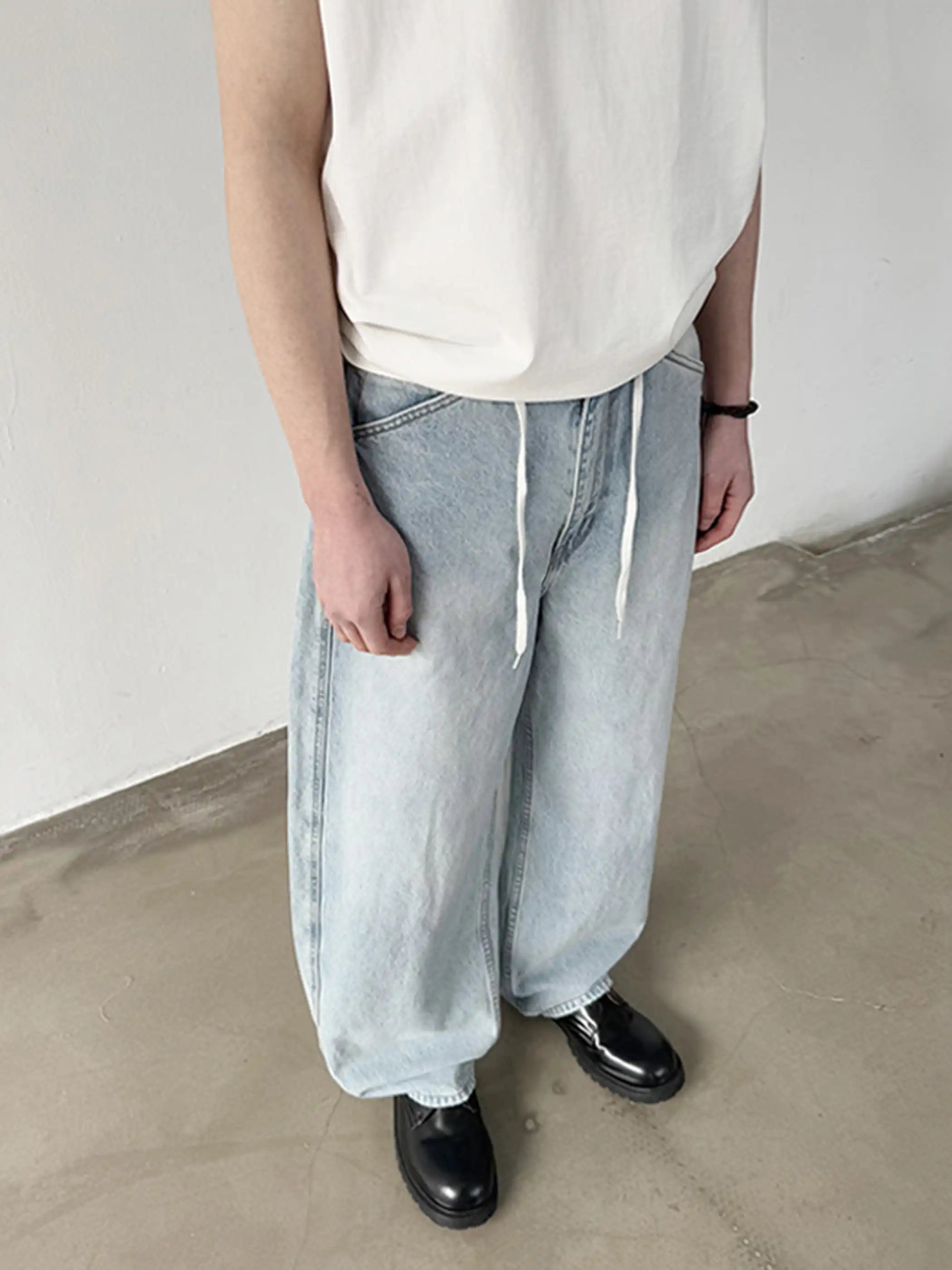 淡いウォッシュ加工が施されたロング丈ワイドデニム、ウエストのドローコードが見える
