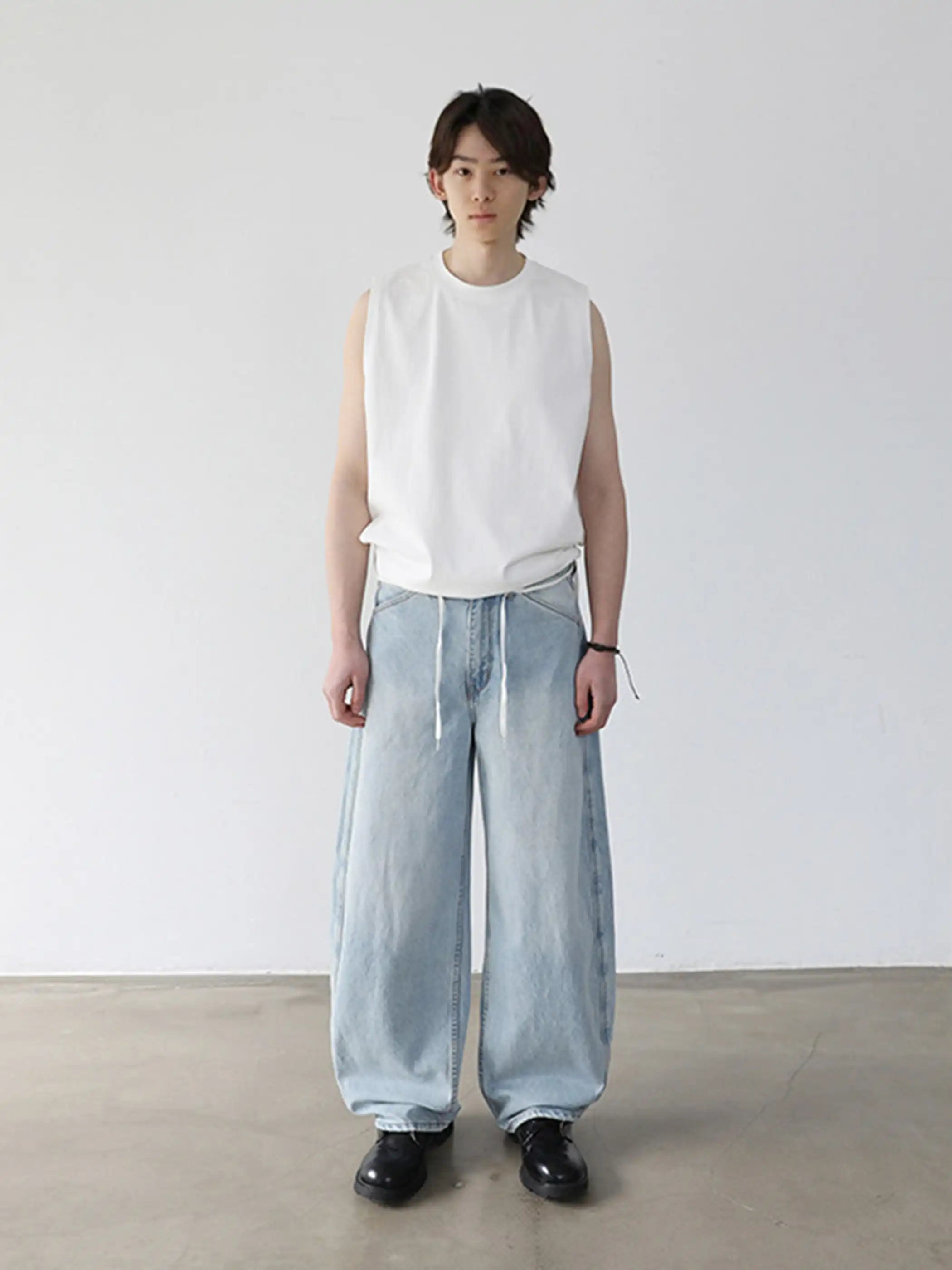 淡いウォッシュ加工が施されたロング丈ワイドデニム、ウエストのドローコードが見える
