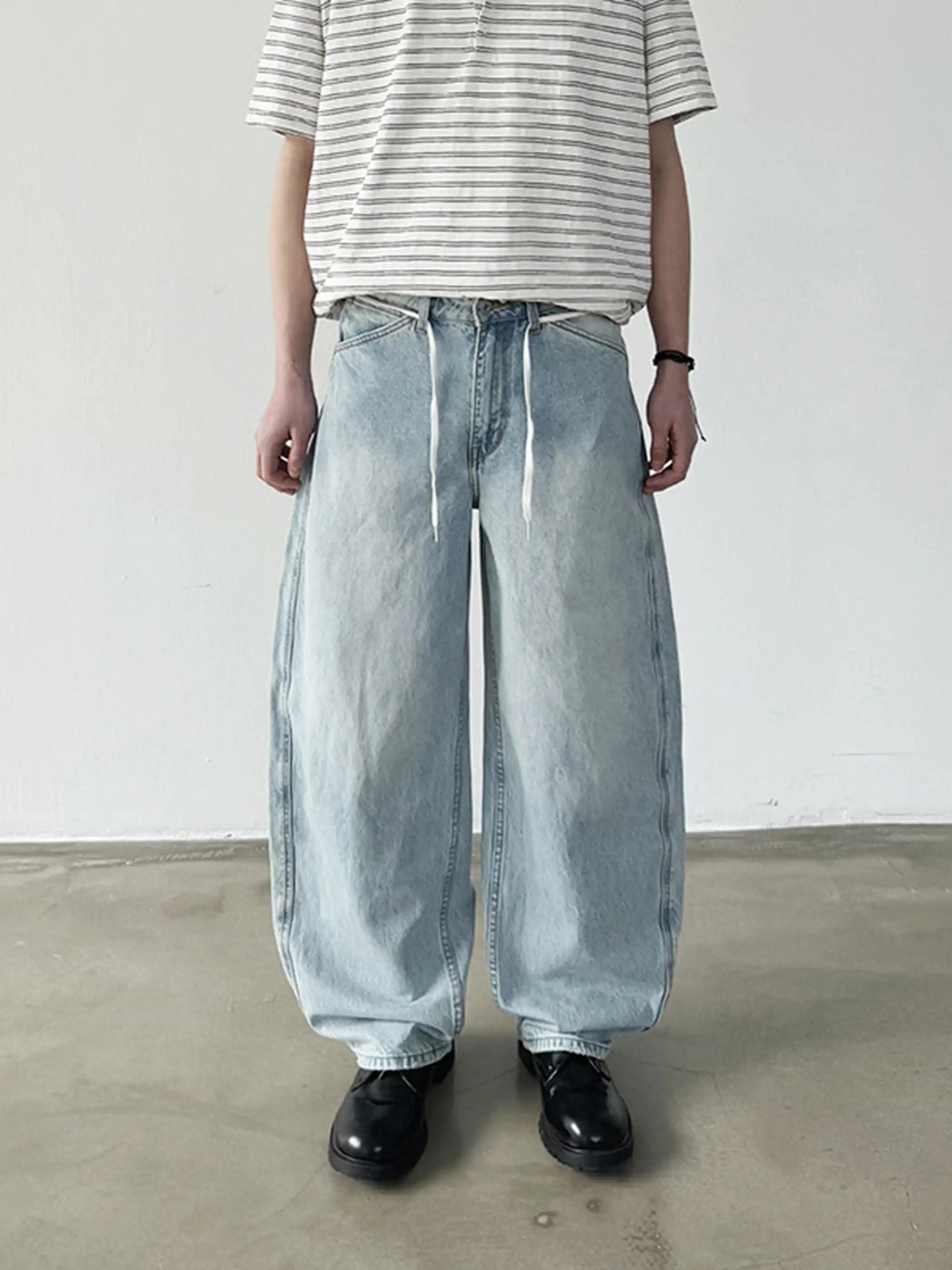 淡いウォッシュ加工が施されたロング丈ワイドデニム、ウエストのドローコードが見える
