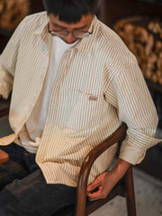 詳細画像: 細ストライプとダブルボタンカフスのディテール
モデル画像: 細ストライプのゆったりシルエットシャツを着用した男性