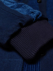 製品画像: 藍染めストライプのコーデュロイスタンドカラージャケット全体像。民族風パッチワークデザインで、太畝のコーデュロイが秋冬に適した温かみを表現。

詳細画像: 藍染めストライプと多機能ポケットのディテール画像。ダイヤ柄キルティング加工の中綿が見える耐久性と保温性の高い仕上がり。