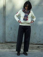 詳細画像：マフラーの織り目とフェアアイランド柄のディテールが鮮明に描かれており、シェトランドウール特有の柔らかな質感と耐久性が伝わります。染色技術にこだわったカラフルな糸が、アクセントとなる美しいデザインを際立たせています。

モデル画像：シェトランドウールのフェアアイランド柄マフラーを着用したモデルが、ヴィンテージ感のあるスタイルでコーディネートしています。マフラーの柔らかさと温かさが際立ち、日常的なカジュアルスタイルにもぴったりのアイテムであることを示しています。