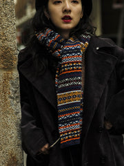 詳細画像：マフラーの織り目とフェアアイランド柄のディテールが鮮明に描かれており、シェトランドウール特有の柔らかな質感と耐久性が伝わります。染色技術にこだわったカラフルな糸が、アクセントとなる美しいデザインを際立たせています。

モデル画像：シェトランドウールのフェアアイランド柄マフラーを着用したモデルが、ヴィンテージ感のあるスタイルでコーディネートしています。マフラーの柔らかさと温かさが際立ち、日常的なカジュアルスタイルにもぴったりのアイテムであることを示しています。