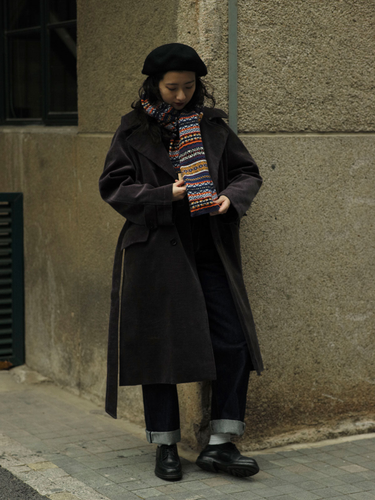 詳細画像：マフラーの織り目とフェアアイランド柄のディテールが鮮明に描かれており、シェトランドウール特有の柔らかな質感と耐久性が伝わります。染色技術にこだわったカラフルな糸が、アクセントとなる美しいデザインを際立たせています。

モデル画像：シェトランドウールのフェアアイランド柄マフラーを着用したモデルが、ヴィンテージ感のあるスタイルでコーディネートしています。マフラーの柔らかさと温かさが際立ち、日常的なカジュアルスタイルにもぴったりのアイテムであることを示しています。