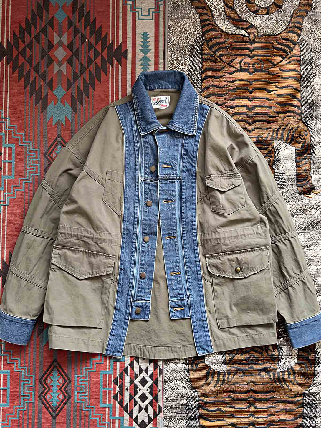 製品画像：
マルチ素材パッチワークデニムジャケットの全体画像。ミリタリーグリーンとデニム素材のパッチワークが特徴的で、ウォッシュ加工によりヴィンテージ感とトレンド感を兼ね備えています。

詳細画像：
ジャケットのパッチワークデザイン、ウォッシュ加工によるユーズド感、ディテールにこだわったボタンとジッパー部分。