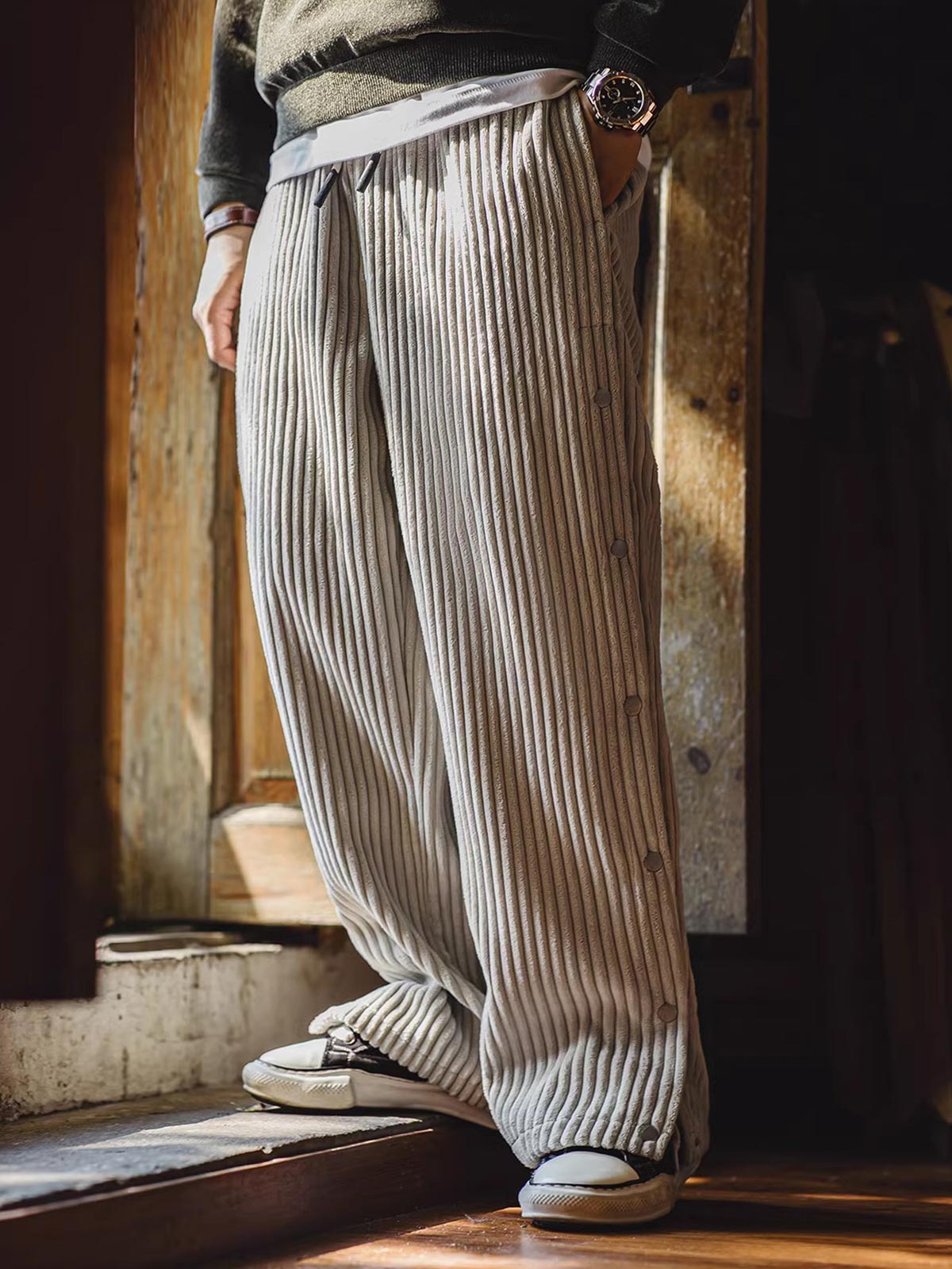 詳細画像（Detail Image）:
サイドのボタンデザイン、ウエスト部分、コーデュロイ素材の質感をクローズアップした画像。ボタンの開閉や生地の触感が伝わるようなディテールが特徴。

モデル画像（Model Image）:
実際に着用したモデルが、ヴィンテージ風コーデュロイボタン付きストレートスウェットパンツをスタイリッシュに着こなしているシーン。シルエットやフィット感が分かるように工夫された着用写真。
