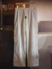 詳細画像（Detail Image）:
サイドのボタンデザイン、ウエスト部分、コーデュロイ素材の質感をクローズアップした画像。ボタンの開閉や生地の触感が伝わるようなディテールが特徴。

モデル画像（Model Image）:
実際に着用したモデルが、ヴィンテージ風コーデュロイボタン付きストレートスウェットパンツをスタイリッシュに着こなしているシーン。シルエットやフィット感が分かるように工夫された着用写真。
