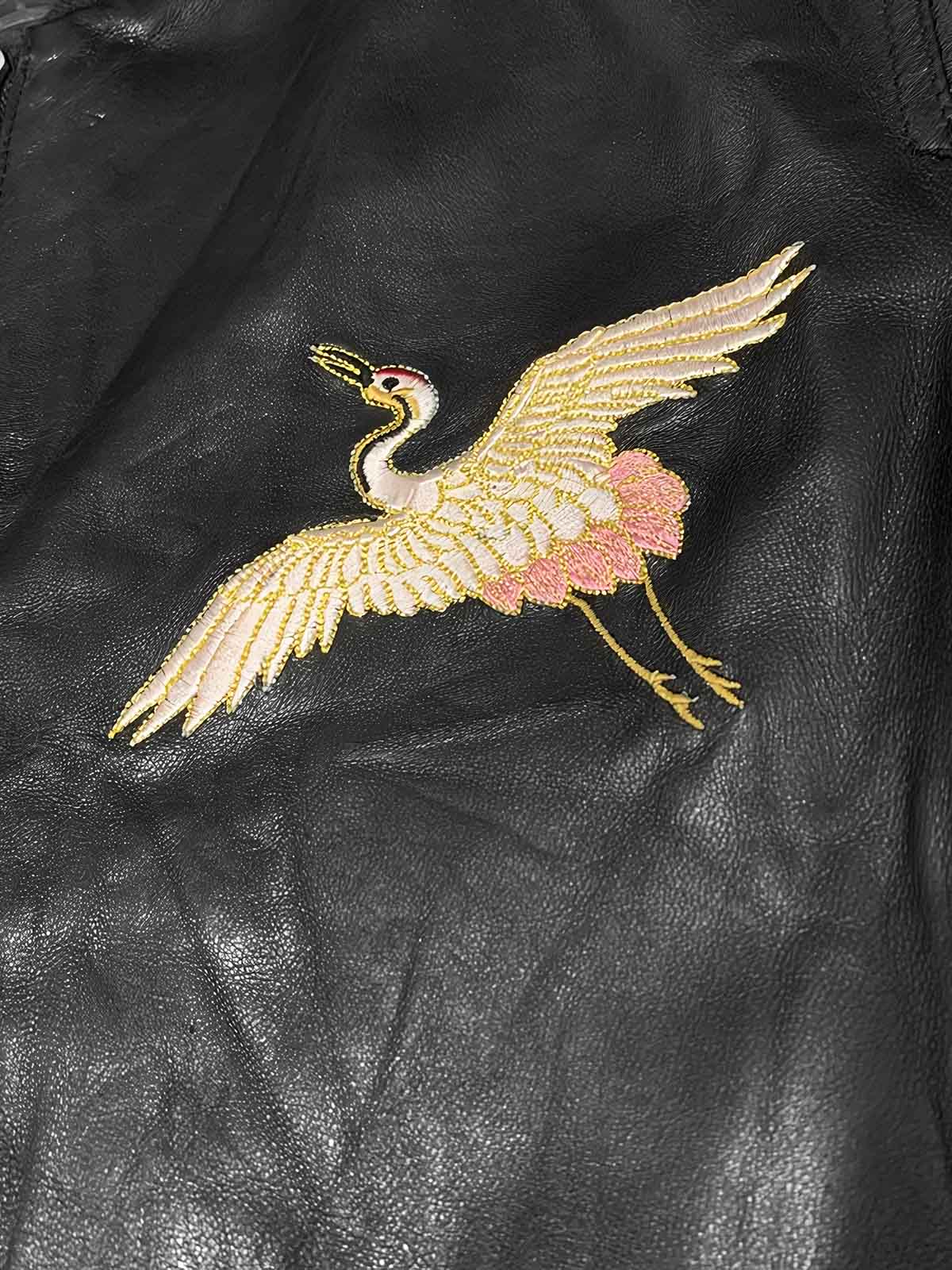 製品画像: 横須賀鶴図刺繍 羊革ジャケット全体画像、吉祥の象徴である「鶴図」刺繍と上質な輸入羊革のデザイン
詳細画像: 横須賀の伝統技法を用いた鶴、松、雲の刺繍ディテール、立体感ある精巧な工芸