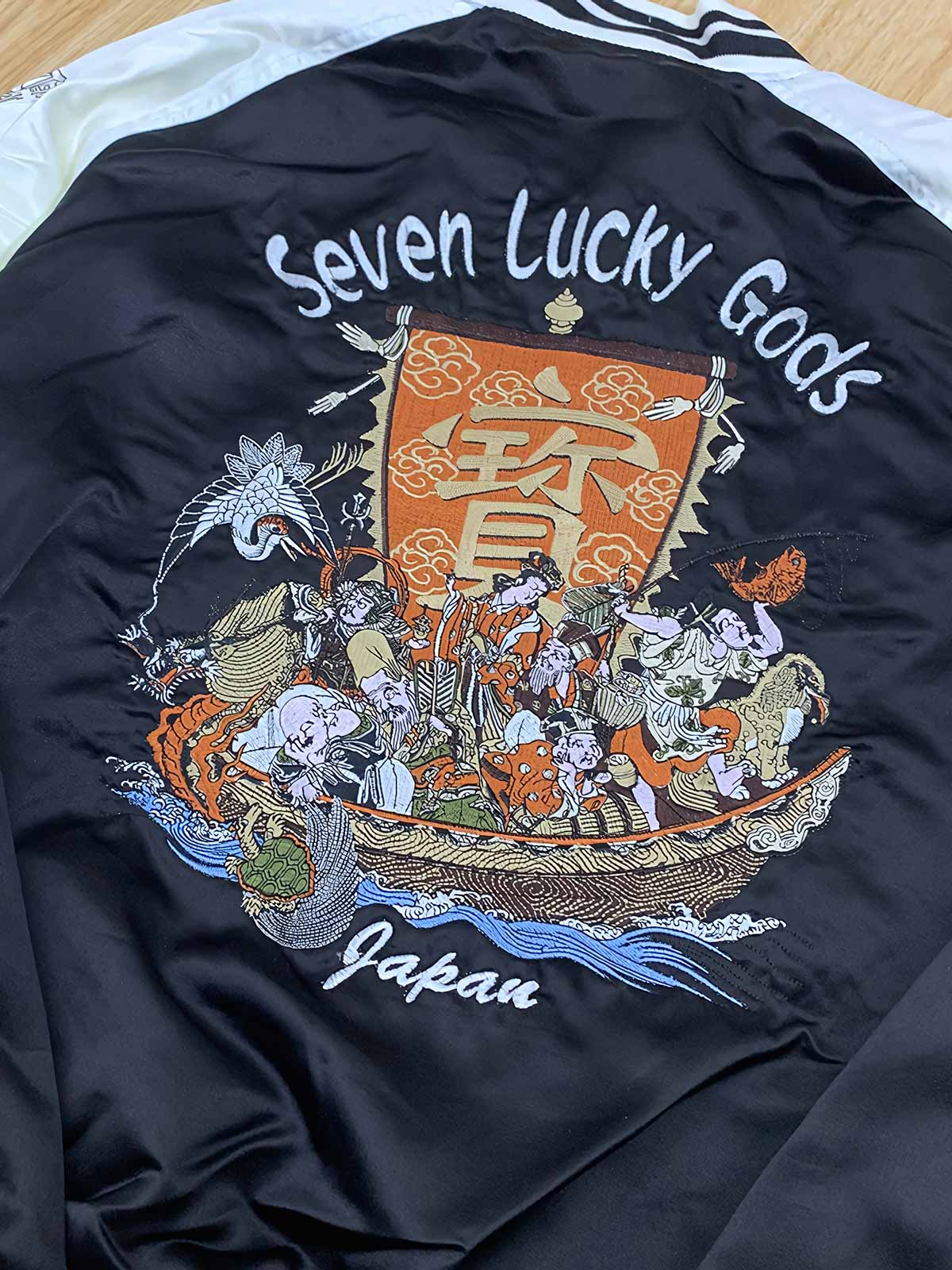 製品画像: リバーシブル シルク刺繍 横須賀 宝船 七福神 ジャケット全体画像、伝統的な横須賀刺繍と幸運の象徴デザイン

詳細画像: 七福神宝船と赤鬼、虎の刺繍ディテール、精緻なシルク刺繍で仕上げられた高級感あるデザイン