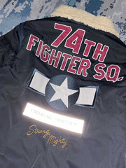 製品画像: 第74戦闘飛行中隊 B3 フライトジャケットの全体画像、シープスキン裏地とクラシックなミリタリースタイル
詳細画像: 背面の「74th FIGHTER SQ.」ロゴとアメリカ空軍マークの刺繍ディテール