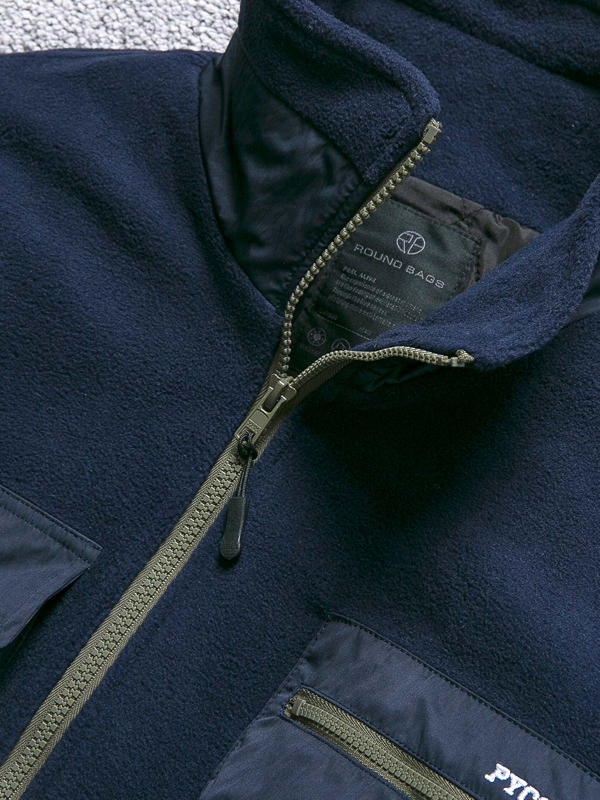 製品画像
カラーブロックフリースジャケットの正面画像。カラーブロックデザインが特徴的な、軽量で保温性に優れたフリース素材を使用した秋冬向けの多ポケットジャケット。

詳細画像
フリース素材を使用したカラーブロックデザインの多機能ポケットが特徴的なジャケットのディテール。収納力を高めるポケットと、立ち襟デザインが秋冬の寒さから守ります。