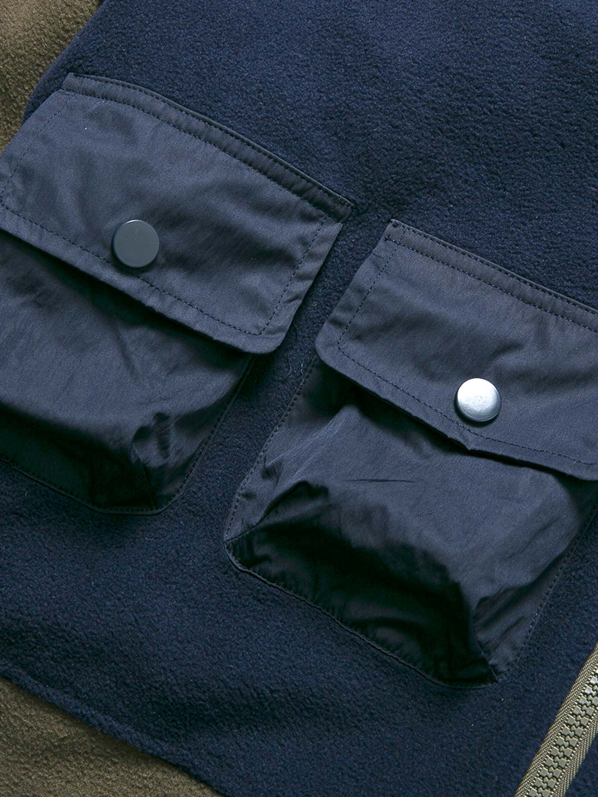 製品画像
カラーブロックフリースジャケットの正面画像。カラーブロックデザインが特徴的な、軽量で保温性に優れたフリース素材を使用した秋冬向けの多ポケットジャケット。

詳細画像
フリース素材を使用したカラーブロックデザインの多機能ポケットが特徴的なジャケットのディテール。収納力を高めるポケットと、立ち襟デザインが秋冬の寒さから守ります。