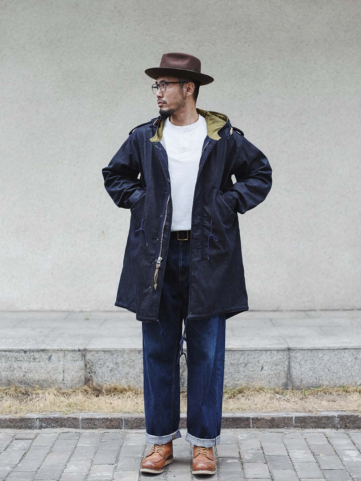 詳細画像： YKK製スナップボタンと特注シルバーカラージッパー、ブルー樹脂ボタンのディテールをクローズアップした画像。ヴィンテージ感を引き立てる丁寧なディテールが際立つ。
モデル画像： モデルがデニムバージョンのM51フィッシュテールコートを着用し、カーゴパンツとスニーカーを合わせたヴィンテージミリタリースタイルのコーディネート画像。軽やかさと保温性を両立した冬のデイリースタイルを提案。