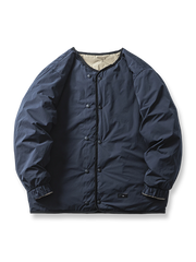 製品画像： リバーシブル撥水・撥油・防汚軽量ダウンジャケットの全体イメージ画像。ホワイトダックダウン90%を使用した中綿と、特別なテフロンコーティングを施した外層が特徴的。グレーベージュとネイビーの両面デザインで、アウトドアから日常コーデまで幅広く活用可能。
詳細画像： 撥水・撥油・防汚加工が施された外層と、軽量ホワイトダックダウン中綿をクローズアップしたディテール画像。耐久性と保温性を兼ね備えた素材が際立つ。