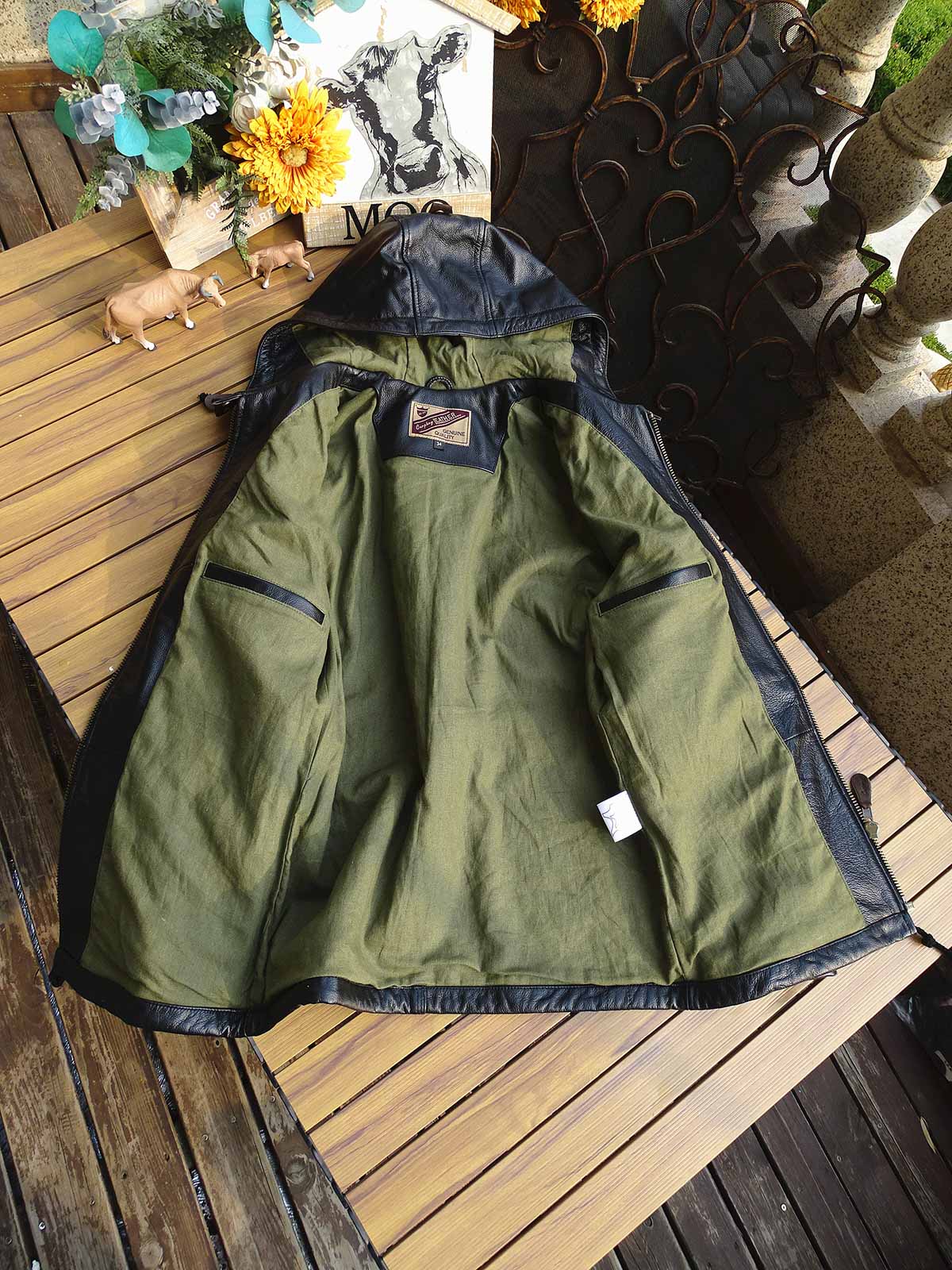 製品画像： 9ポケットフィールドフード付きフルグレインレザージャケット全体イメージ画像。黒いシボ加工レザーとヴィンテージ感漂うオイル仕上げのスエードディテールが特徴で、アウトドアやバイクライドにも適した多機能デザイン。
詳細画像： YKKアンティークブロンズジッパーとオイルドスエードレザーの補強ディテールをクローズアップした画像。耐久性とクラシックな風合いが際立つ仕上がり。