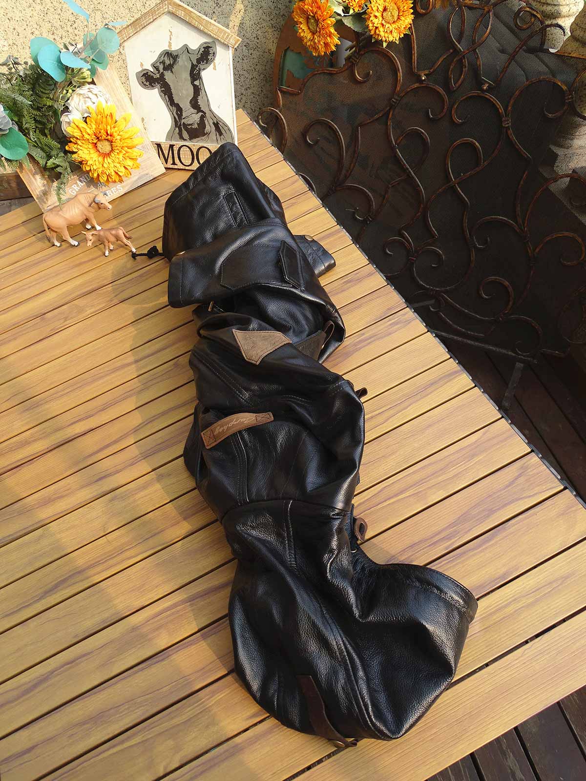 製品画像： 9ポケットフィールドフード付きフルグレインレザージャケット全体イメージ画像。黒いシボ加工レザーとヴィンテージ感漂うオイル仕上げのスエードディテールが特徴で、アウトドアやバイクライドにも適した多機能デザイン。
詳細画像： YKKアンティークブロンズジッパーとオイルドスエードレザーの補強ディテールをクローズアップした画像。耐久性とクラシックな風合いが際立つ仕上がり。