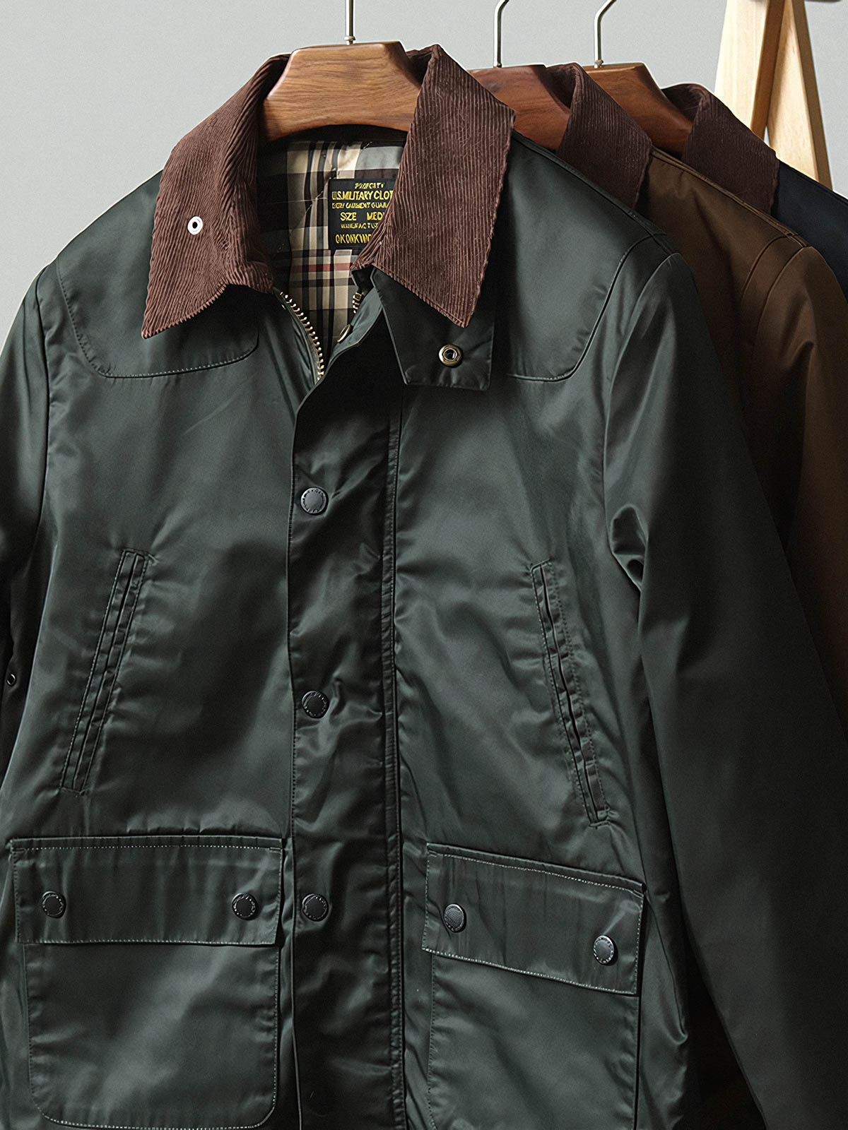 製品画像: コーデュロイカラーのコントラスト襟とオイルワックス加工が施されたハンティングジャケット。高密度梭織生地を使用し、耐久性とレトロ感を兼ね備えたデザイン。

詳細画像: チェック柄のキルティングライニングとスナップボタン付き風防襟のディテール。YKKのダブルヘッドラウンドリングジッパーと多機能ポケット配置が実用性を高めています。