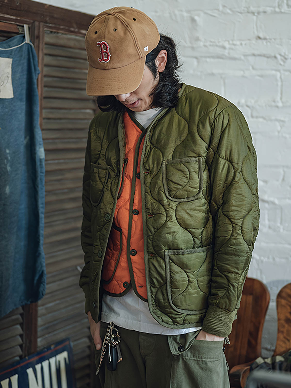 詳細画像: リバーシブルデザイン（オリーブグリーンとレスキューオレンジ）、袖口のリブ編みが冷気をシャットアウト。軽量でありながら優れた保温性を提供。

モデル画像: モデルが弧形キルティングインナーダウンジャケットを着用、ルーズフィットシルエットと防水性に優れた素材で、秋冬のレイヤードスタイルを演出。