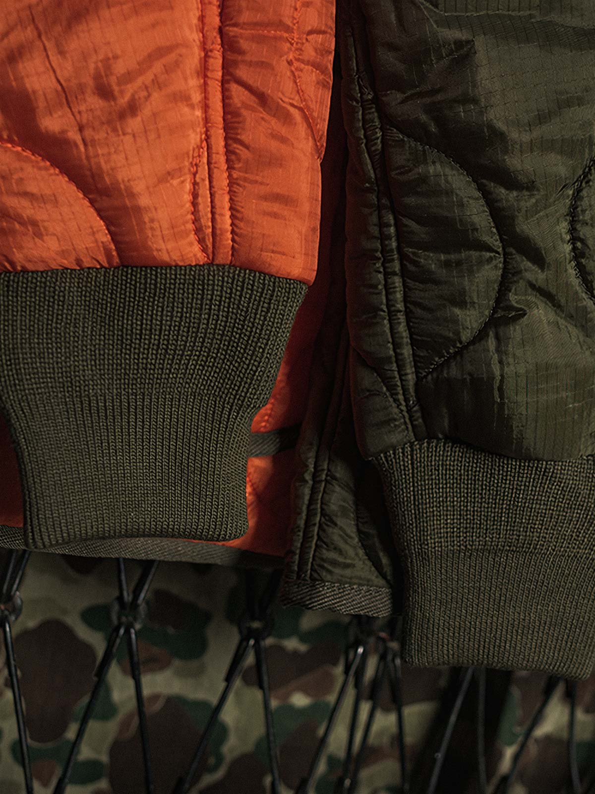 製品画像: 弧形キルティングデザインの軽量インナーダウンジャケット、ミリタリースタイルでレトロ感と現代的な機能性を兼ね備えた秋冬の必須アイテム。

詳細画像: リバーシブルデザイン（オリーブグリーンとレスキューオレンジ）、袖口のリブ編みが冷気をシャットアウト。軽量でありながら優れた保温性を提供。
