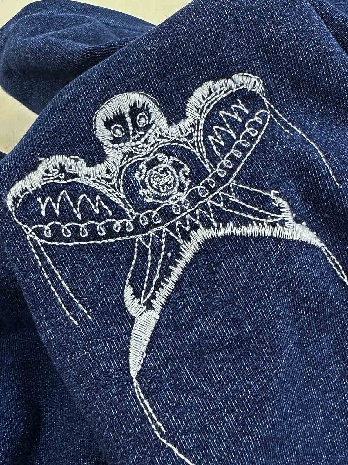 製品画像：藍染めスワローカイト刺繍スウェット、伝統的な藍染め技法と繊細なスワローカイト刺繍が融合した個性的なデザイン。100%コットン素材を使用し、自然なグラデーション効果と肌に優しい着心地が特徴。

詳細画像：スワローカイト刺繍のディテールアップ、藍染め技法による美しいグラデーション効果と、精梳コットン表地とシルク風中綿を使用した高級感あるデザイン。植物染色技法で自然な美しさを強調。