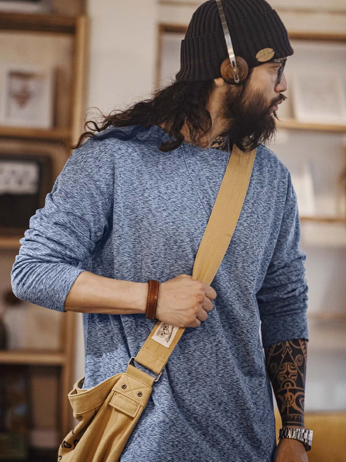 詳細画像: カチオン糸による独特な風合いとヴィンテージ感漂うブラウンのレザーパッチのディテールをクローズアップした画像。見た目の個性と高級感を強調。
モデル画像: 両面フリース起毛 長袖Tシャツを着用したモデルが、リラックスしたカジュアルコーディネートを披露。インナーとしても単独でも活躍するアイテム。
