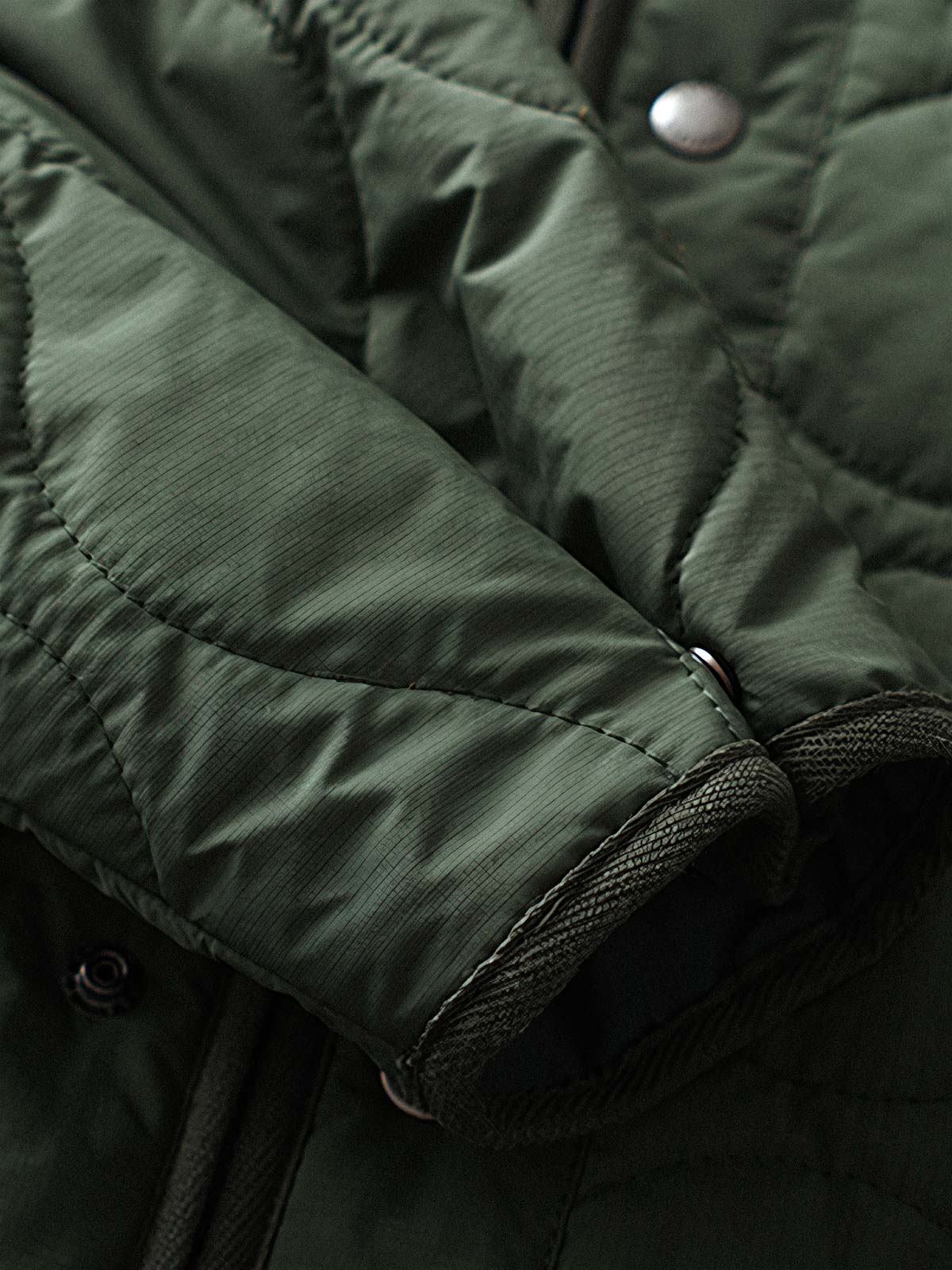 製品画像
「テフロン加工 三防テクノロジー ダイヤキルティング中綿ジャケット全体像。防水、防油、防汚の三防機能と3M™シンサレート中綿が特徴で、軽量で暖かい冬のアウター」

詳細画像
「テフロン加工 ダイヤキルティング中綿ジャケットのダブルジッパーとスナップボタンのディテールクローズアップ。防風性とデザイン性を両立」