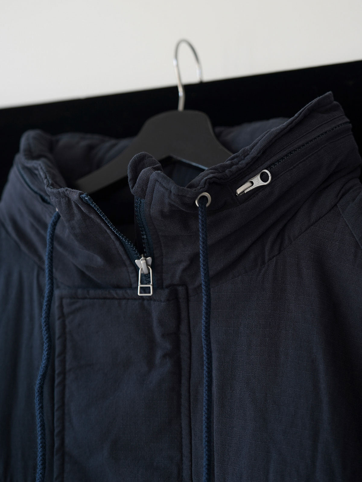 詳細画像
「ペイズリー柄の裏地と日本製YKK製の両開きファスナーのディテールを特写した画像。ヴィンテージデザインと高機能性を兼ね備えたジャケット。」

モデル画像
「モデルがトーンオントーン パッチワーク ミドル丈中綿ジャケットを着用し、デニムパンツと合わせた冬のアウトドアカジュアルスタイルを披露。」