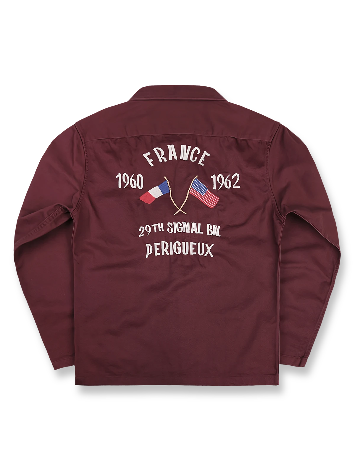 製品画像
厚手キャンバス生地で作られた刺繍キャンバスシャツの全体画像。1960年代のミリタリーユニフォームを再現したヴィンテージ感あるデザインが特徴。

詳細画像
フランス・ペリグーとアメリカ・カリフォルニア州をモチーフにした繊細な刺繍ディテールのクローズアップ。実用的なフラップ付きポケットも強調。