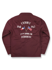 製品画像
厚手キャンバス生地で作られた刺繍キャンバスシャツの全体画像。1960年代のミリタリーユニフォームを再現したヴィンテージ感あるデザインが特徴。

詳細画像
フランス・ペリグーとアメリカ・カリフォルニア州をモチーフにした繊細な刺繍ディテールのクローズアップ。実用的なフラップ付きポケットも強調。