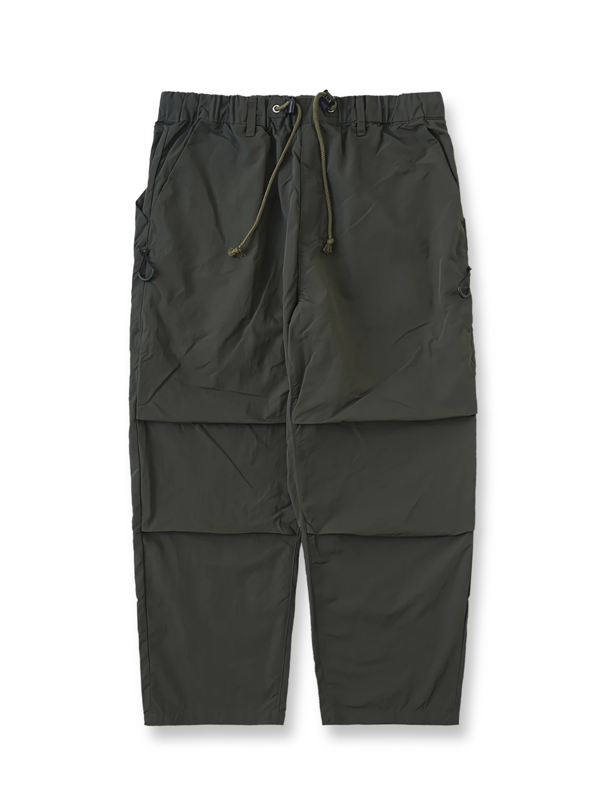 製品画像
撥水性に優れたナイロン素材を使用し、シワ感テクスチャーが特徴のミリタリーパラシュートパンツ全体画像。ダブルプリーツと多機能ポケットを備えたクラシックなシルエットが際立つデザイン。

詳細画像
膝部分のダブルプリーツディテール、隠しポケット、UTX Duraflexドローコードエンド、そして反戦をテーマにしたデュポン紙ラベルのクローズアップ画像。機能性とディテールへのこだわりを強調。