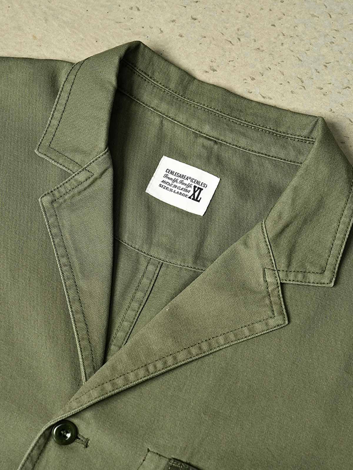 製品画像
「ウォッシュ加工を施したワークテイストテーラードジャケット全体イメージ。スーツのフォーマル感とワークウェアの実用性を融合し、ヴィンテージ感を演出したデザイン。」

詳細画像
「バイカラーの胸ポケットやアシンメトリーな複合ポケットのディテールクローズアップ。酵素ウォッシュ加工による自然な色褪せ感と軽い起毛感が特徴。」