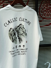 東洋の水墨画がプリントされた『水墨丹青』短袖Tシャツのフロントビュー。自然景観の繊細な描写が特徴のアートピース。水墨画プリントTシャツのネックラインとダブルステッチのショルダーラインのクローズアップ。精緻なプリント技術と生地の質感が確認できる。